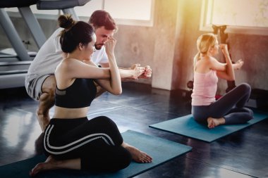 Genç kadın ve erkekler spor salonunda sağlıklı vücut egzersizleri, spor tarzı yoga konsepti yapıyor.