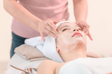 Güzel genç kadın spa masaj alma rahatlatıcı yüze kozmetik krem uygulayarak, Spa yüz konsepti