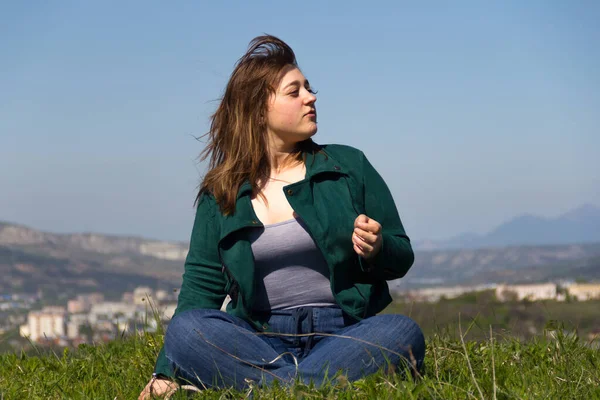 Beautiful Curvy Girl Green Jacket Jeans Sits Lotus Position Looks — Stock Photo, Image