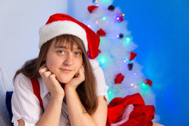 Genç bir kadın Noel ağacının yanında yanaklarını kaldırır ve gülümser.