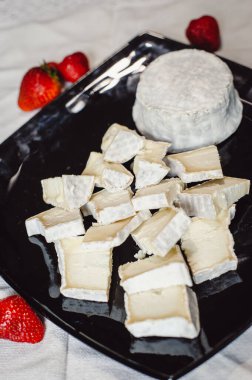 Siyah tabakta dilimlenmiş beyaz küflü Fransız yumuşak peyniri. Peynir bileşimi.