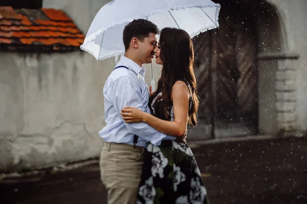 幸せなカップル 男性と女性の街の雨の中を歩くのが大好きです 雨が降っているときに白い傘の下でキスをする女の子と男 閉じる — ストック写真