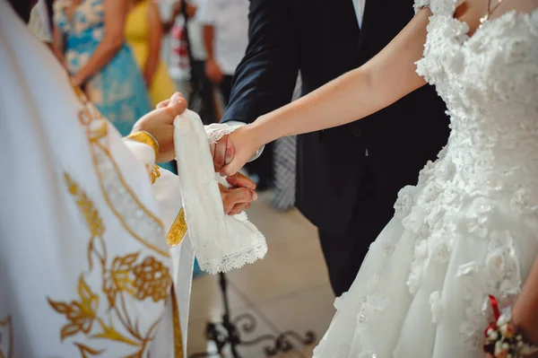 新娘和新郎的手绑着婚纱 关门了 牧师把新娘的手巾捆起来 新娘在教堂举行的婚礼上 — 图库照片