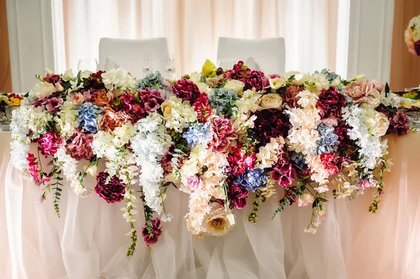 A festive table decorated with a composition of pink, white, blue hydrangea flowers, in the banquet hall. Newlyweds table in banquet area for wedding. Closeup, composition of different flowers, on a festive table.