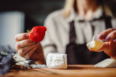 Beyaz küflü yumuşak Fransız peyniri. Çilekli camembert peyniri tatmış bir kadın..
