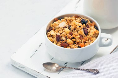 Tropikal meyve ve ahşap tahta üzerinde beyaz süt kabı ile müsli fincan. Saf tonlarda sağlıklı beslenme kavramı