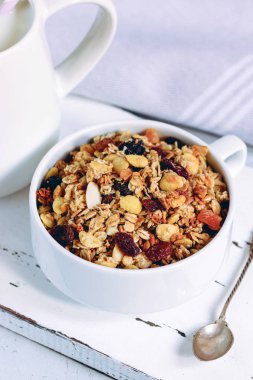 Tropikal meyve ve ahşap tahta üzerinde beyaz süt kabı ile müsli fincan. Saf tonlarda sağlıklı beslenme kavramı.