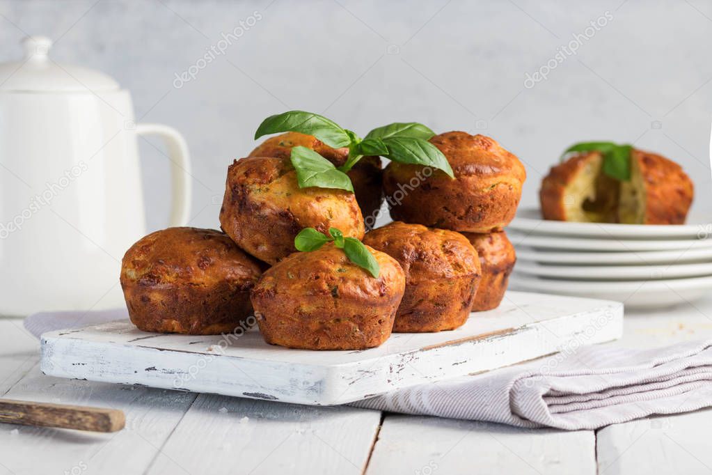Homemade freefly baked double cheese muffins with basilic on a white wooden board. Healthy snack or breakfast meal