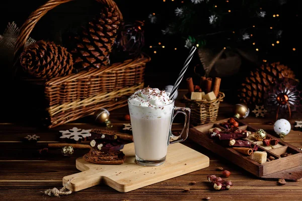 Hot chocolate drink with whipped cream. Cozy Christmas composition on a dark wooden background. Sweet treats for cold winter days