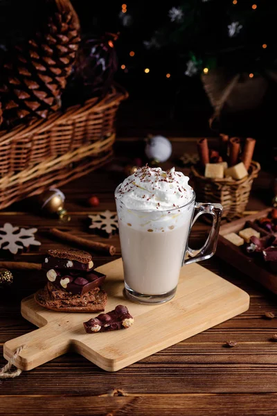 Hot chocolate drink with whipped cream. Cozy Christmas composition on a dark wooden background. Sweet treats for cold winter days