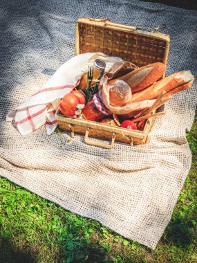 Meyve, ekmek ve kavanoz bej ekose kayısı reçelli piknik sepeti dolu.