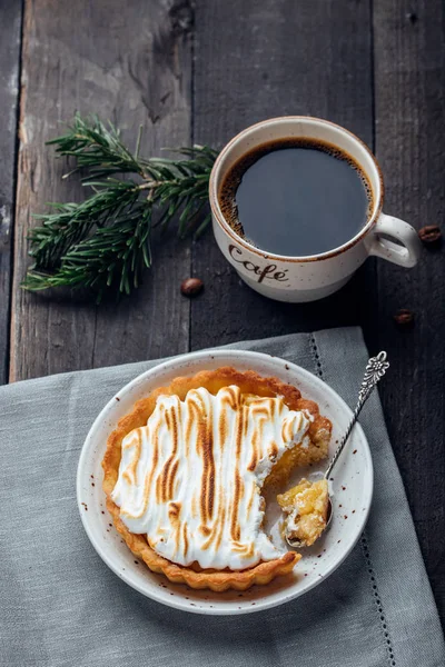 Delicious Christmas Dessert. Lemon tart with meringue and cup of coffee on dark wooden table. Christmas Holiday Decoration