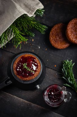 Küçük çikolata ev yapımı kek kiraz reçeli ile süslenmiş. Karanlık moody tarzı. Üstten görünüm, seçici odak.