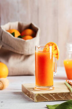 Bir bardak taze sıkılmış portakal suyu ve kan portakal ahşap masa üzerinde. Yaz parlak ruh hali.