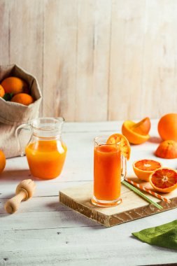 Bir bardak taze sıkılmış portakal suyu ve kan portakal ahşap masa üzerinde. Yaz parlak ruh. Üstten Görünüm