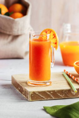 Bir bardak taze sıkılmış portakal suyu ve kan portakal ahşap masa üzerinde. Yaz parlak ruh hali.