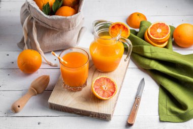 Bir bardak taze sıkılmış portakal suyu ve kan portakal ahşap masa üzerinde. Yaz parlak ruh. Üstten Görünüm