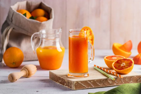 Стакан свежевыжатого апельсинового сока и кровавые апельсины на деревянном столе. Яркое летнее настроение. Вид сверху — стоковое фото