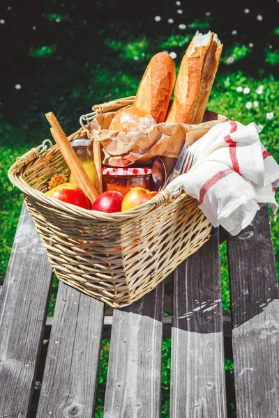 Cesta de picnic llena de fruta, pan y tarro con mermelada de albaricoque — Foto de Stock