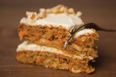 Tahta masada tatlı çatalıyla kesilmiş bir dilim havuçlu kek.