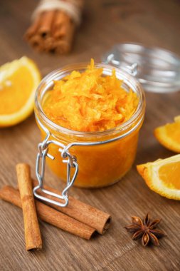 Portakal, tarçın ve yıldız anason dilimli bir kavanoz turuncu konfeksiyon ahşap zemin üzerinde ev yapımı portakal reçeli ahşap masada birkaç parça ekmek ile ev yapımı portakal reçeli ahşap masa üzerinde birkaç parça ekmek