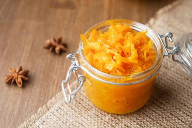 Çuval bezi ve ahşap arka planda yıldız anasonlu bir kavanoz turuncu turuncu turuncu reçel ve çuval ağacının üzerinde birkaç parça ekmek.