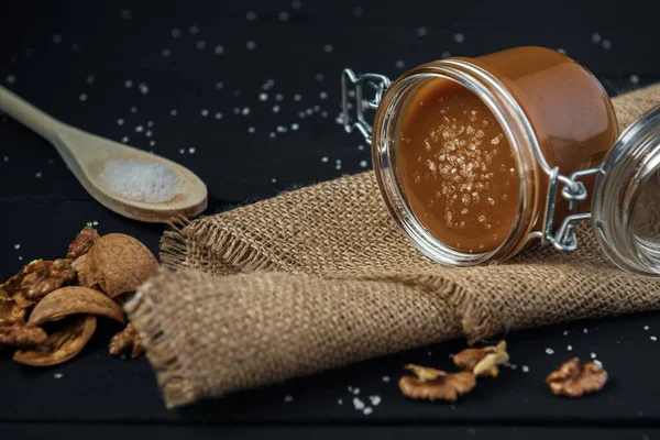 Glass Jar Salted Caramel Wooden Spoon Salt Walnuts Nutshells Black — Stock Photo, Image