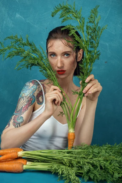 Fashion Female Tattooed Model Sitting Blue Table Bunch Carrots Freckled — Stock Photo, Image