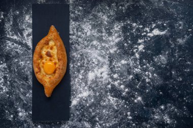 Adjarian Khachapuri - Gürcü peynirli ekmek. Peynirli ve yumurtalı üç açık turta. Parşömen ve beyaz Provence tarzı arka planda doluyor..