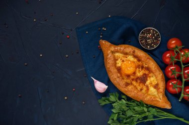 Dilimlenmiş Adjarian Khachapuri - Gürcistan peynirli ekmek ve çatal ile koyu mavi desenli arka plan. Peynir ve yumurta sarısı dolgulu fırında turta. Yemek tamamlama.