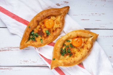 Dilimlenmiş Adjarian Khachapuri - Gürcistan peynirli ekmek ve çatal ile koyu mavi desenli arka plan. Peynir ve yumurta sarısı dolgulu fırında turta. Yemek tamamlama.