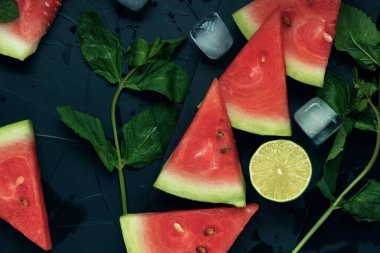 Karpuz dilimleri, nane, kireç ve buz koyu dokulu arka planda. Düz yatıyordu. Yakın plan. Üst görünüm.