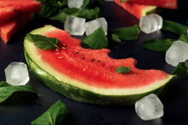 Nane yapraklı karpuz dilimi ve siyah desenli arkaplanda buz küpleri.. 