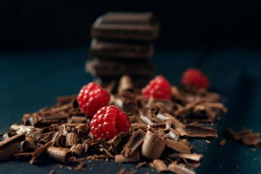 Koyu ahşap arka planda çikolata parçacıkları ve ahududu.
