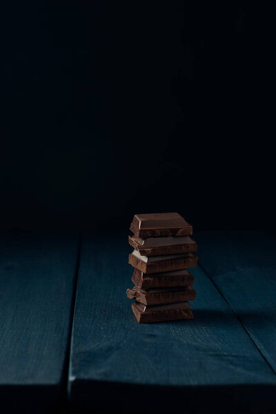 Куча шоколадных кусочков на темно-синем деревянном столе. Принято. Пространство для текста.