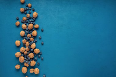 Mavi arka planda dağılmış ceviz ve yaban mersini. Düz yatıyordu. Boşluğu kopyala.