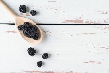 Beyaz Provence tarzı masada böğürtlenli ahşap kaşık. Uzayı kopyala Düz yatıyordu.