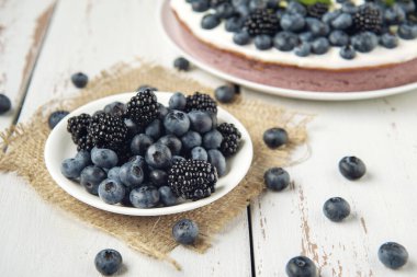 Arka planda böğürtlen ve yabanmersinli tabak peçete ve süzme peynirli güveç.. 