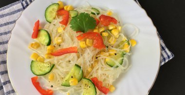 Sebzeli salata tabağı ve Çin eriştesi, siyah arka plan, yakın plan.