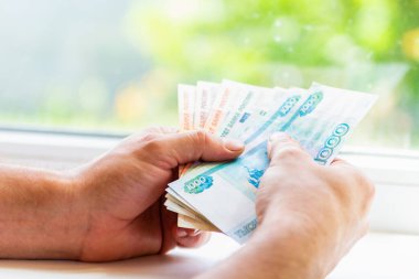 Erkeklerin elinde 5000 ve 1000 rublelik banknotlar var. Rus parası. Rusça 