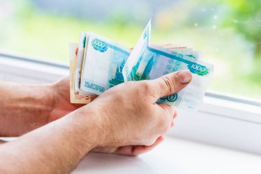 Erkeklerin elinde 5000 ve 1000 rublelik banknotlar var. Rus parası. Rusça 