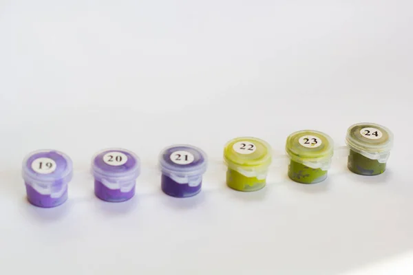 Small colored paint jars. Numbered by numbers. Close-up. On a light background. Place for an inscription. The background.