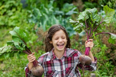 Ekose gömlekli komik, koyu renk saçlı bir kız bahçede gülüyor ve hasat yapıyor. Yaz. Ağustos. Yakın plan..