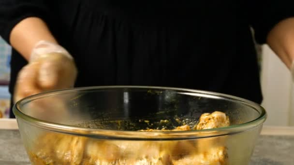 Chef mengen rauwe kippenpoten voor barbecue of bakken in diepe glazen kom met marinade. Specerijen en saus worden gemengd met kippenpootjes. Close-up. — Stockvideo