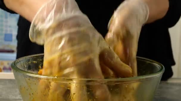 Šéfkuchař míchá syrové kuřecí stehýnka na grilování nebo smaží v hluboké skleněné míse s marinádou. Koření a omáčka se mísí s kuřecími stehny. Detailní záběr. — Stock video