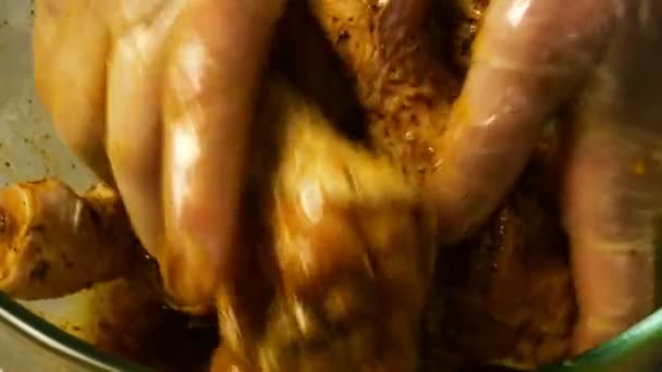 Chef mixt rohe Hühnerkeulen zum Grillen oder Braten in einer tiefen Glasschüssel mit Marinade. Gewürze und Soße werden mit Hühnerkeulen vermischt. Nahaufnahme. — Stockvideo