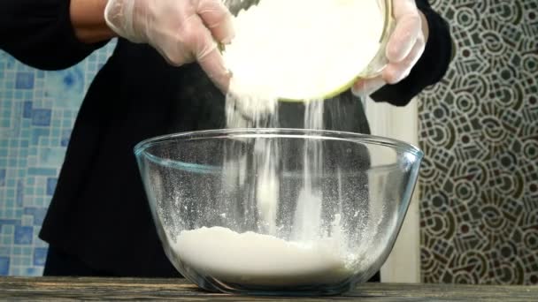 La cocinera prepara la masa para hornear. Vierta la harina de trigo en un recipiente de vidrio transparente, agregue el kéfir, la sal, el machelo de oliva y el huevo. Primer plano . — Vídeo de stock