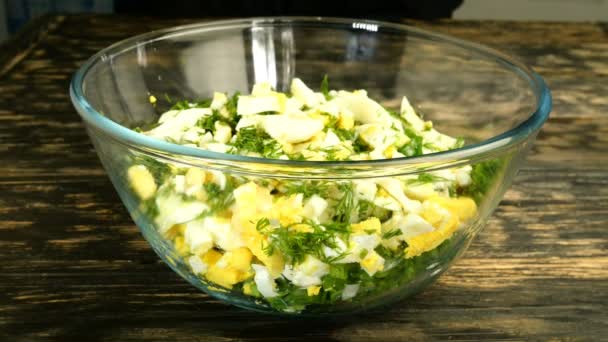 Готуємо яєчний салат з зеленою цибулею. Нарізані цибулини і варені курячі яйця, кріп і сіль змішані з оливковою або рослинною олією в скляній прозорій мисці. Крупним планом . — стокове відео