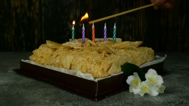 Delicioso bolo soprado Napoleão, no qual com um jogo longo se acendem por cinco velas em honra do aniversário. Close-up . — Vídeo de Stock