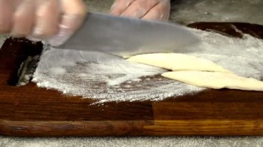 Şefin yaptığı dilimlenmiş hamur hamuru, khvorost ya da faworki kurabiyelerinden lezzetli hamur işleri yapmaya kadar. Yakın plan. Makro.